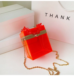 Detail of orange acrylic box bag showing gold metal frame and thick chain handle
