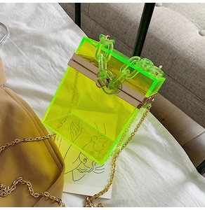 Detail of neon green acrylic box bag with chunky chain handle and gold metal hardware