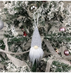 Close-up of a Christmas gnome hanging on a snowy tree branch with white beard detail