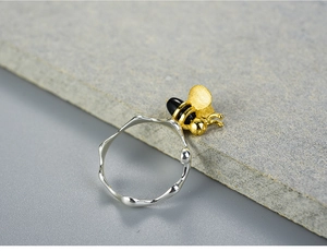 Detailed macro view of a 925 silver bee ring with gold wings and irregular textured band