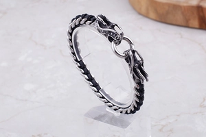 Detailed view of braided leather bracelet with twin vintage steel dragon heads