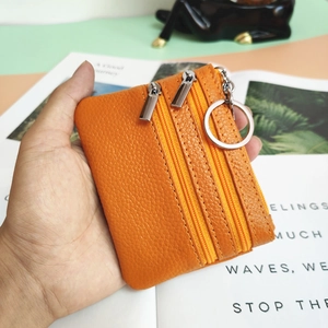 Orange lychee leather coin purse with three zippers and a metal keychain ring
