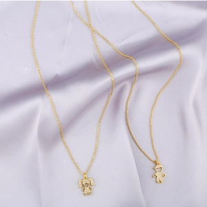 Golden boy and girl silhouette pendants with zircon pavé on purple silk fabric