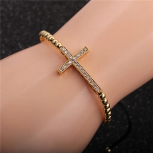 Close-up of gold-plated cross bracelet with micro-p鑲ed zircons on a beaded cord