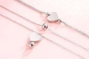 Gros plan détaillé d'un bracelet multi-rangs argenté avec cœur sur fond rose doux