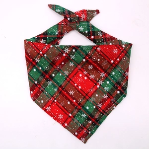 Detail of red and green plaid pet bandana with white snowflake prints and fabric texture