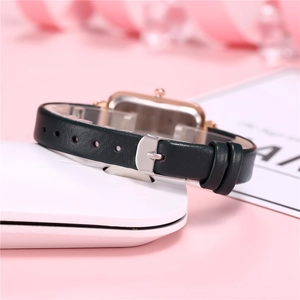 Detailed close-up of dark green leather strap and gold buckle on a square quartz watch