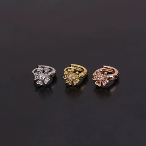 Three flower-shaped ear cuffs in silver, gold, and rose gold with clear zircon centers
