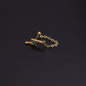 Detail of golden lightning bolt earring with colorful zircons and delicate chain on black
