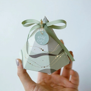 Detail of light green pyramid paper gift box with ribbon and with love tag