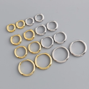 Detailed view of minimalist gold and silver hoop earrings in various sizes on grey background