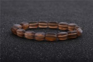 Macro shot of dark brown moonstone beads with matte texture on black textured background