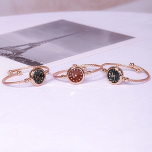 Three elegant rose gold bangle watches with starry dials displayed on a white surface