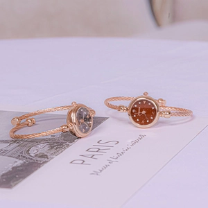 Detail of rose gold open bangle watch with twisted wire band and starry sky dial