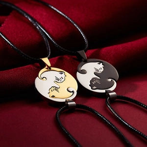 Macro shot of gold and black cat puzzle pendants merging into a circle on red satin