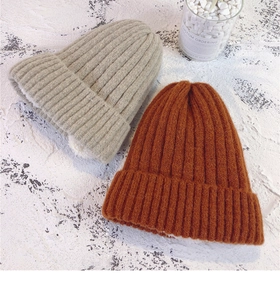 Detail view of winter knitted beanie with thick faux fleece lining in beige and orange
