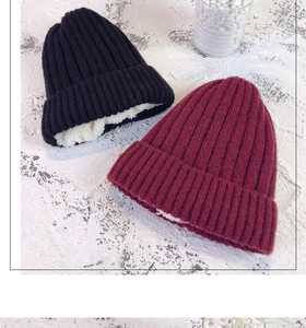 Detail of black and burgundy knit beanies featuring warm white faux fleece lining