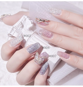 Close-up of pink and purple glitter nails with butterfly and dragonfly metal charms