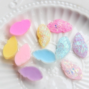 Macro shot of colorful resin conch shell charms for DIY slime and crafts on white dish