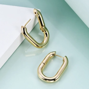 Polished 18K gold-plated U-shaped oval hoop earrings on a geometric display