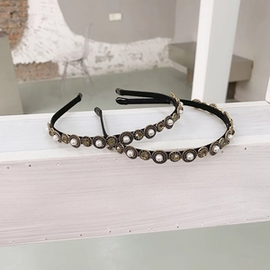 Close-up of baroque headband with white pearls and champagne rhinestones on wood