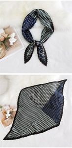 Detail of pleated silk scarf showing geometric green and navy pattern on plush texture