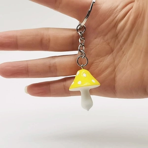 Close-up of yellow resin mushroom keychain with white dots and silver metal ring