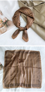 Detail of a brown silk square scarf with black herringbone pattern on a trench coat