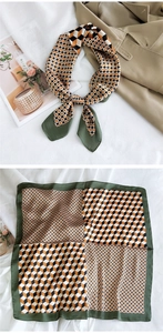 Detail of geometric print silk scarf in green and orange styled on a beige trench coat