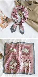 Detail view of pink silk scarf with carriage patterns worn on a beige trench coat