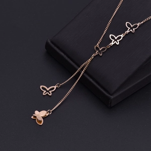 Élégant collier en titane or rose avec pendentifs papillons ajourés sur un fond noir uni