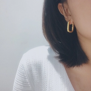 Detail showing an 18K gold-plated U-shaped earring on model for minimalist style