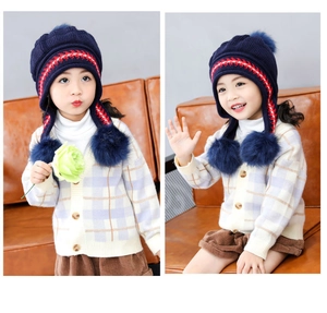 Dettaglio cappello invernale in maglia blu scuro per bambini con motivi geometrici e pompon