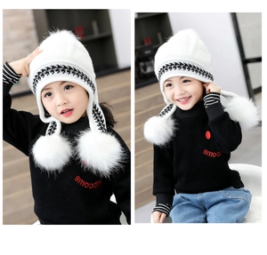 Detailed view of white houndstooth knit hat with three fluffy faux fur pom-poms for girls