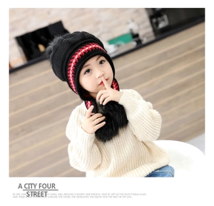 Detailed close-up of kids winter knit hat with pom-poms and matching warm sweater