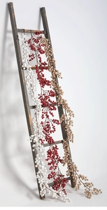 Détail de guirlandes de baies de Noël rouges, blanches et dorées sur une échelle en bois