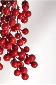 Macro de baies de Noël artificielles rouges brillantes sur une tige brune naturelle