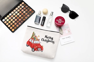 Flat lay of a cotton linen Christmas makeup bag with red car print and festive accessories
