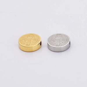 Detail of gold and silver stainless steel beads featuring embossed figures and engravings
