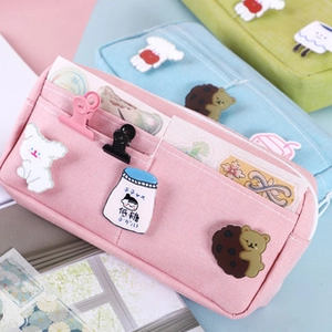 Detalle de estuche rosa con múltiples compartimentos y lindos broches de caricaturas