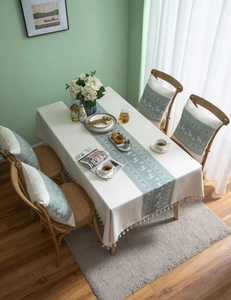 Detail of beige Christmas tablecloth with green reindeer patterns and elegant tassels