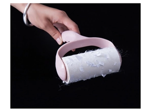 Pink lint roller effectively removing hair and debris from clothes on black background
