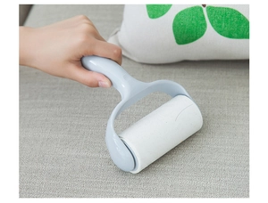 Handheld light blue lint roller removing dust from grey fabric sofa surface