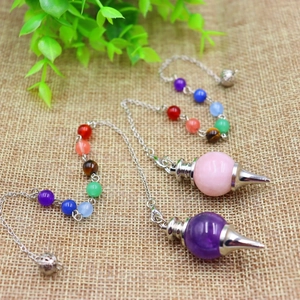 Chakra crystals pendulum with 7 stones on hemp fabric background detail view