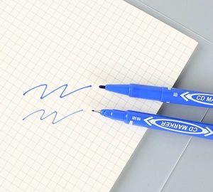 Blue dual-tip permanent marker showing fine and extra-fine strokes on grid paper