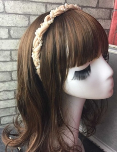 Detail of twisted fabric headband with white pearls and gold rhinestones on hair model