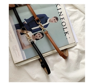 Detail of slim black and brown belts with gold buckles on a Kinfolk magazine