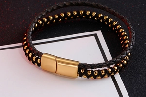 Detailed close-up of double-layer black leather braid and gold beads with magnetic clasp