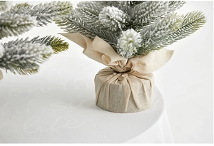Detail of flocked mini Christmas tree with linen wrapped base and rustic bow tie