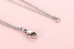 Macro shot of silver metal lobster clasp and chain links on elegant pearl necklace